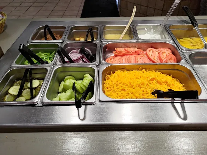 Close-up of the salad bar toppings, shredded cheddar, sliced tomato, red onion, and peppers